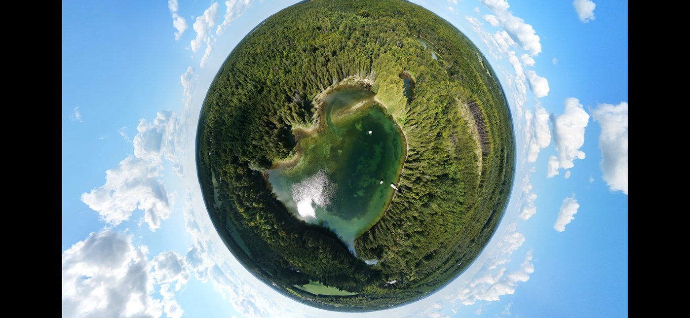 Tiny planet aerial panorama over a forest lake